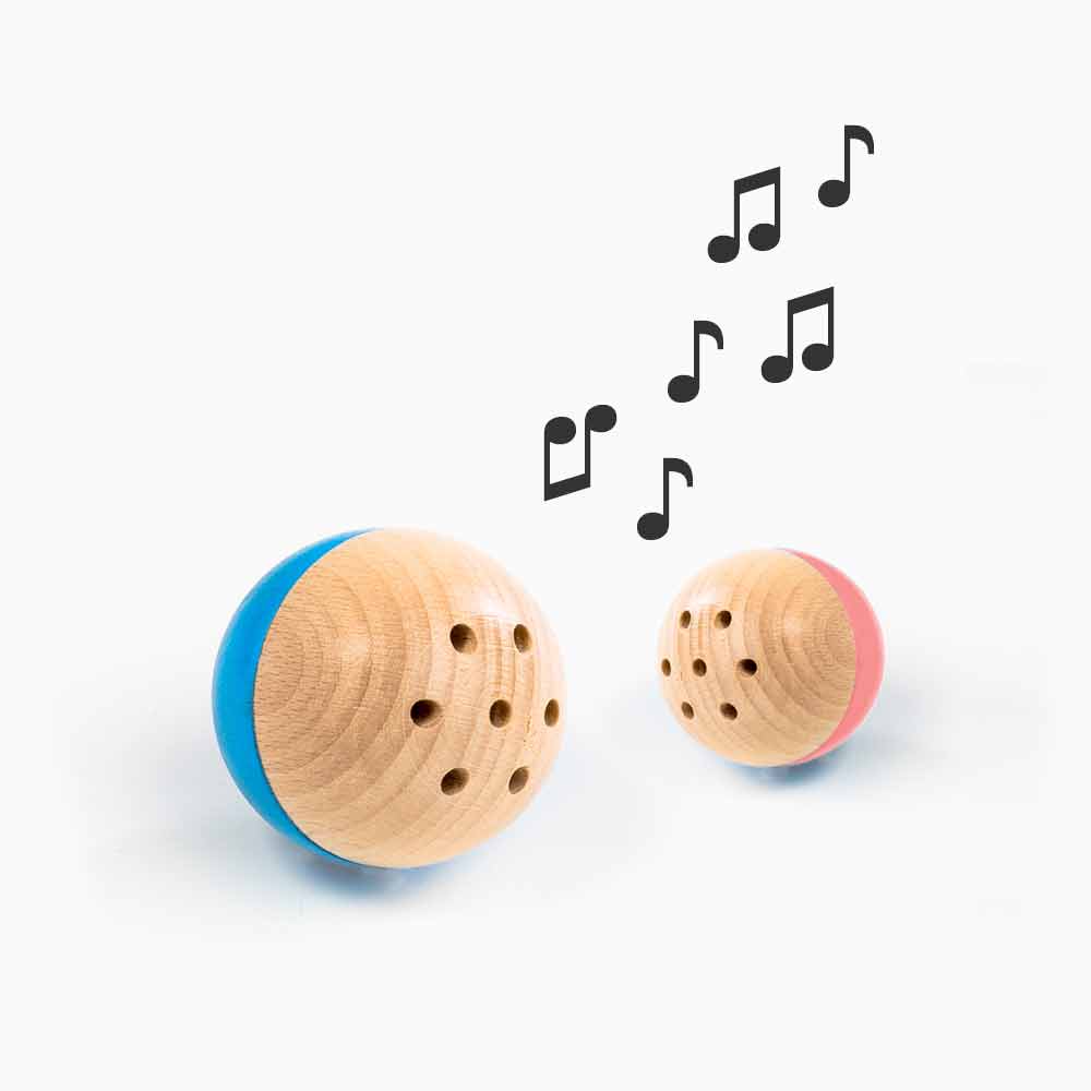 baelly-musik-v5 rewoodo Babyspielzeug Baelly in den Farben blau und rosa zusammen mit Noten die einen Ton andeuten, der aus dem Inneren des Balls durch ein Edelstahlglöckchen ertönt.